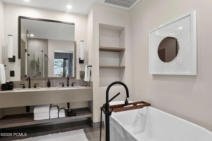 Primary bath with a double vanity, freestanding soaking tub and matte black fixtures.
