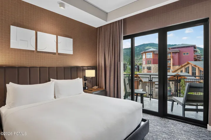 Primary bedroom with a sliding door to the private balcony and Canyons Village mountain views.