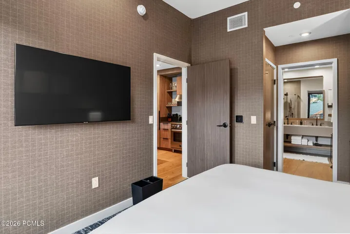 Guest bedroom with a mounted television and direct access to the bath.
