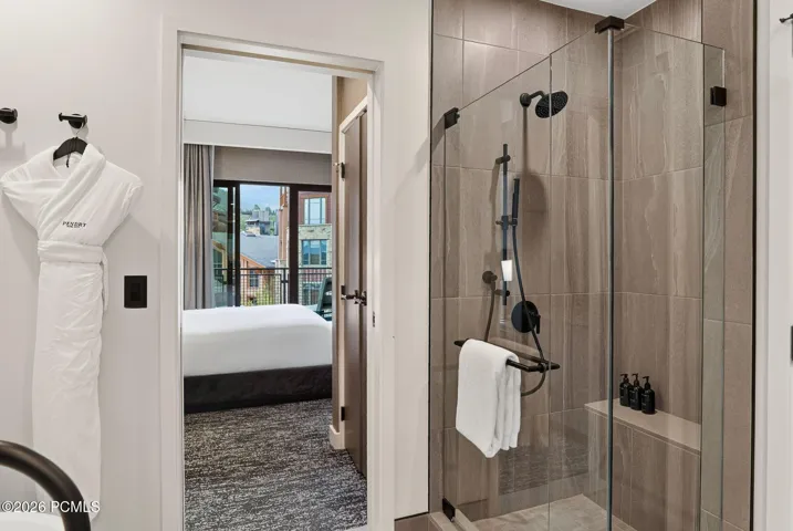 Primary bath walk in shower with bench seating and spa robes, open to the bedroom.