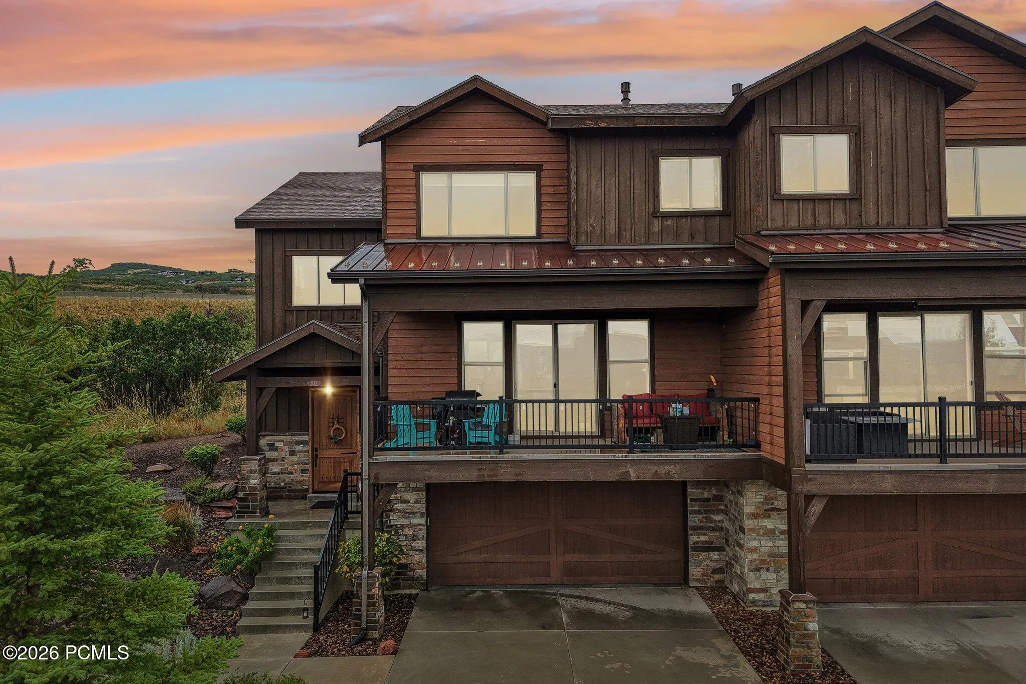 Twilight rendering of the rear elevation with a lit deck and glowing windows in Rustler at Hideout; sky digitally enhanced, deck, siding and view as built.