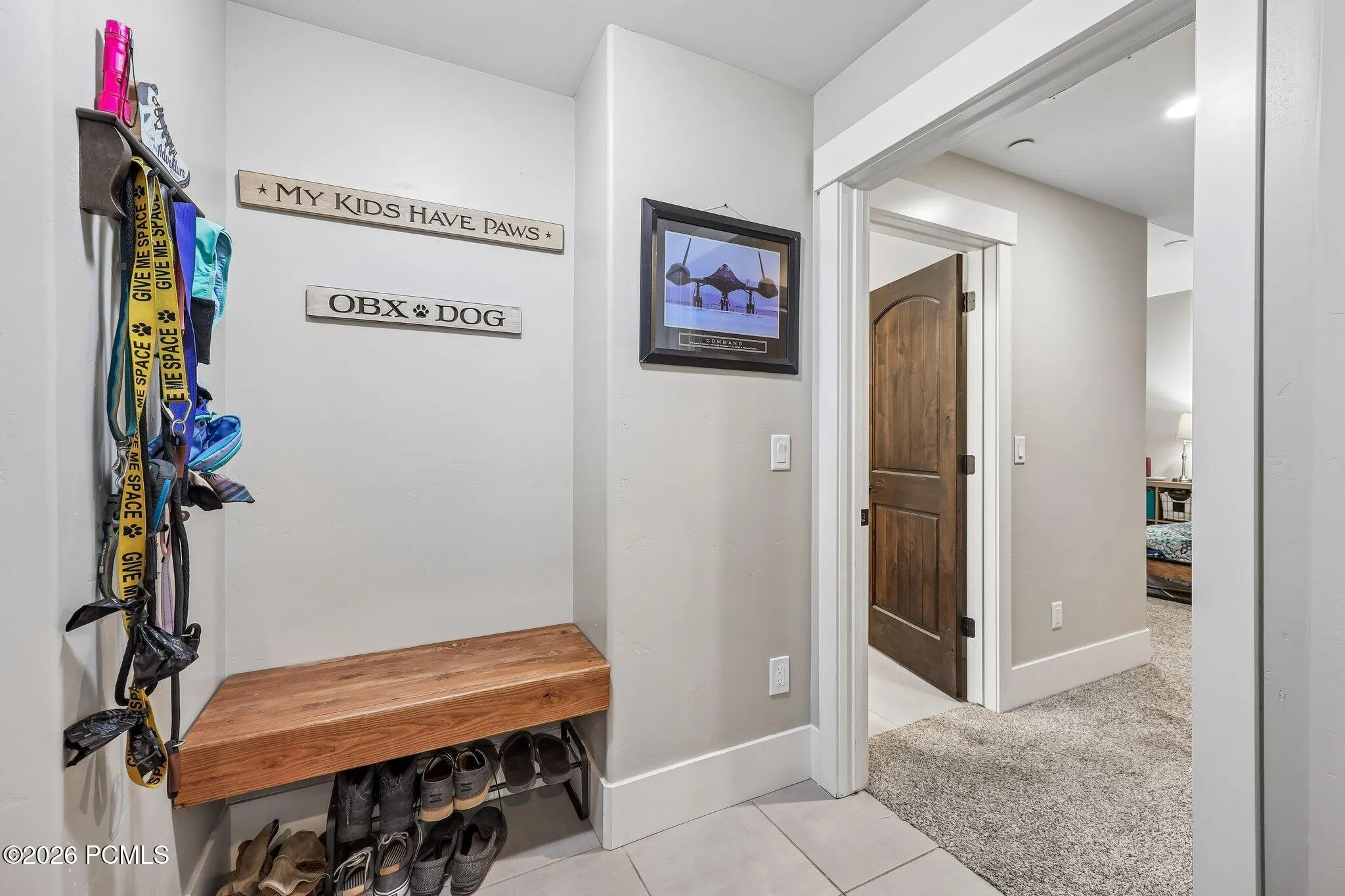 Mudroom gear drop with wall hooks, a wood bench and boot storage opening to the garage in a Hideout, Utah mountain home.