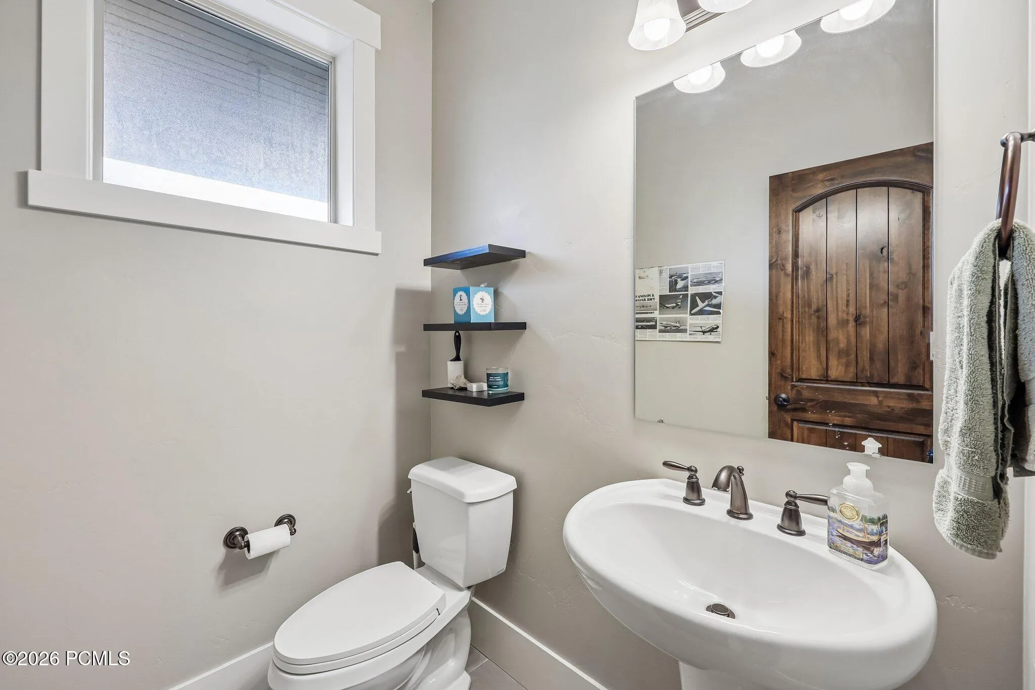 Main-level powder bath off the kitchen with a pedestal sink and knotty alder door in a Hideout, Utah mountain home.