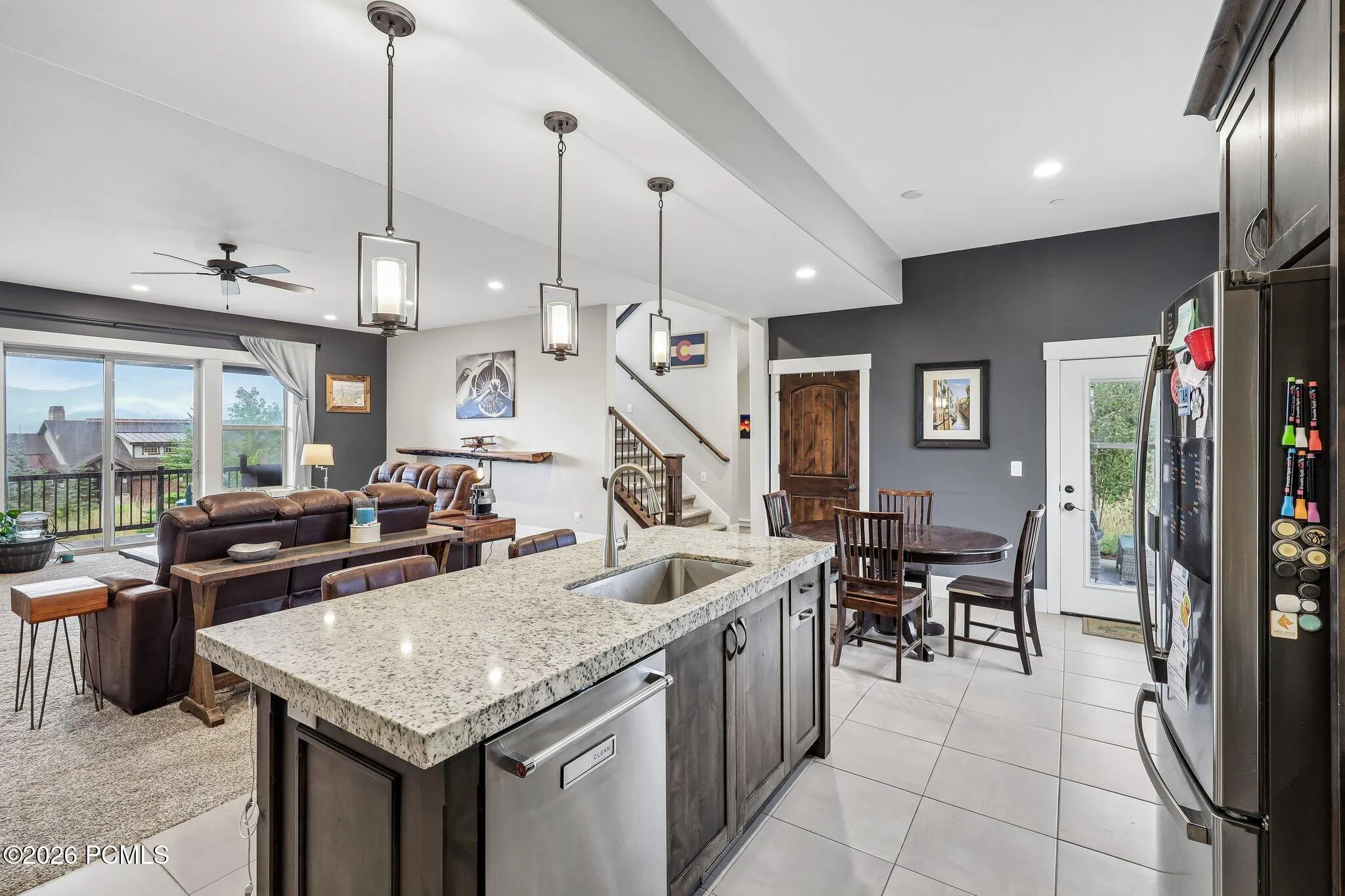 Kitchen island sightline across the great room to the stone fireplace, covered deck and Jordanelle Reservoir beyond, in Hideout, Utah.