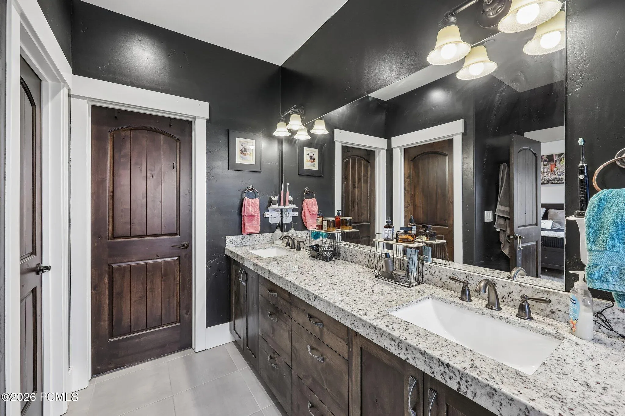 Primary bathroom with a double granite vanity, framed mirrors and a dark accent wall in a Rustler at Hideout home.