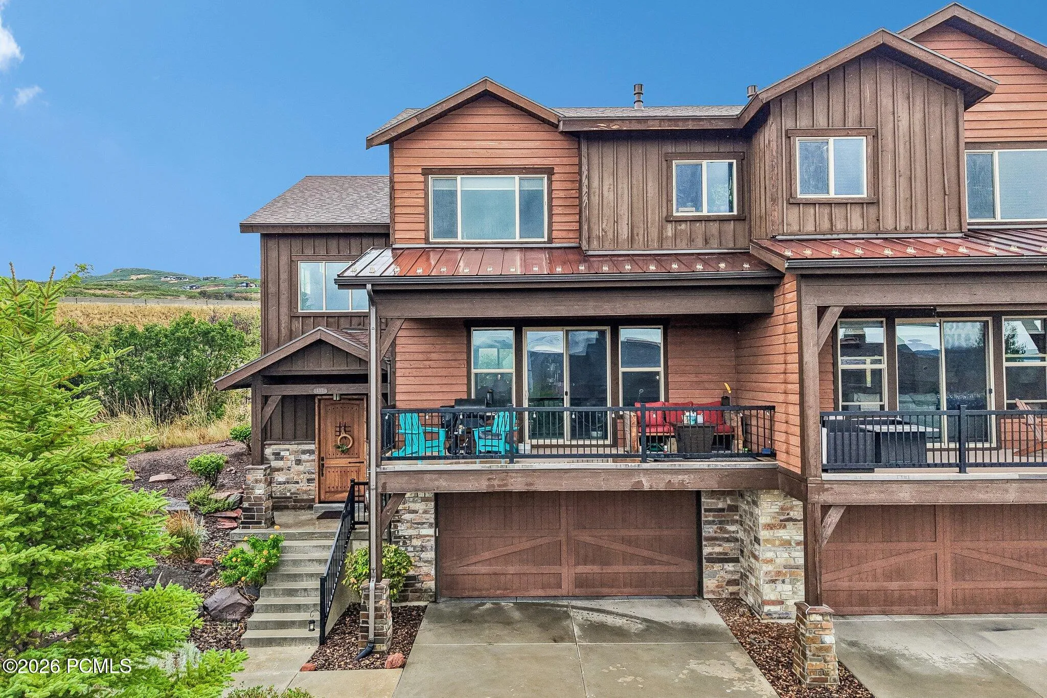 Wood-and-stone front elevation of a Rustler at Hideout home in Hideout, Utah, with a covered main-level deck and tuck-under two-car garage.