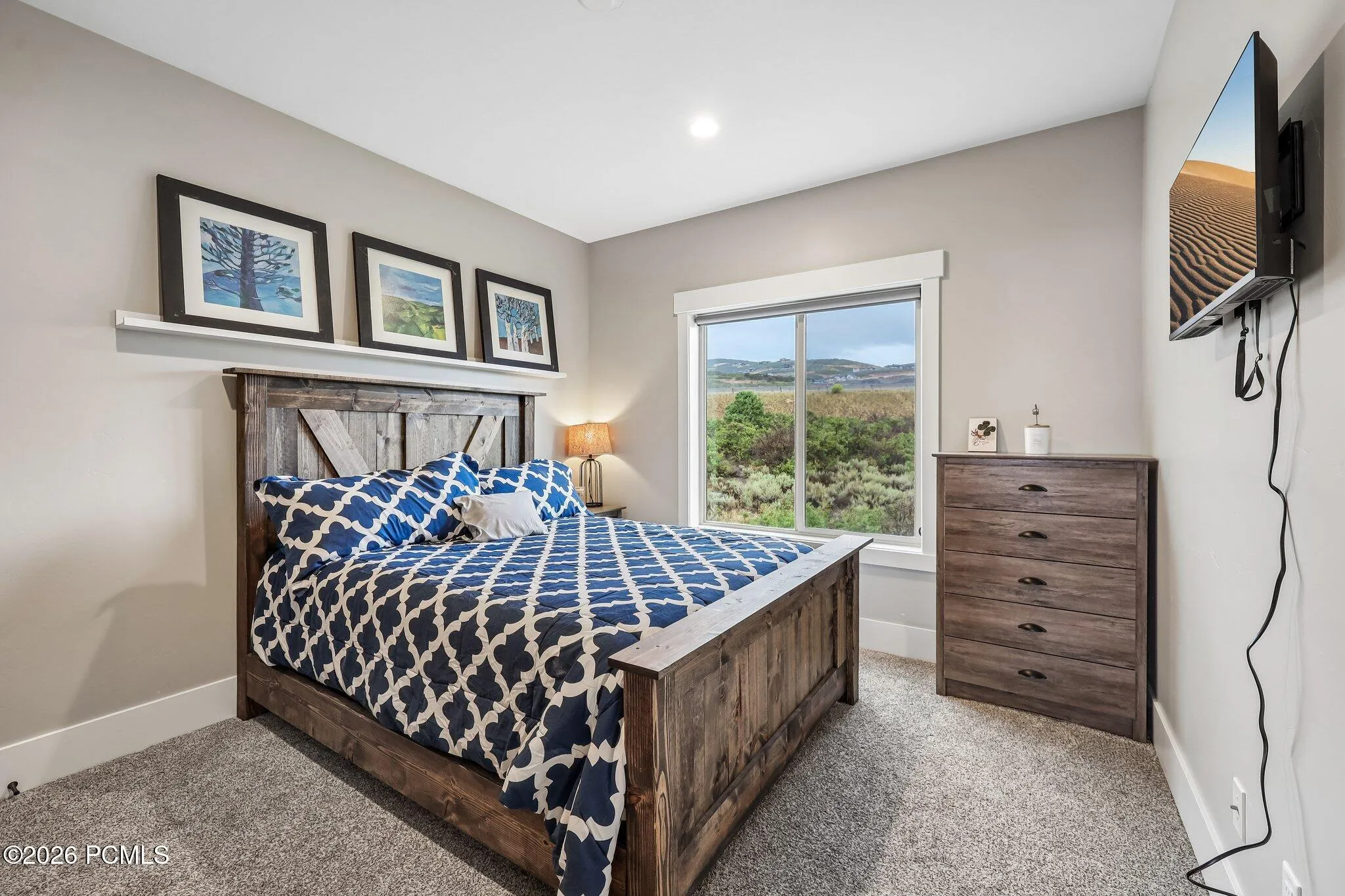 Upstairs guest bedroom with a queen bed, ridgeline window view and wall-mounted TV in a Rustler at Hideout home in Hideout, Utah.