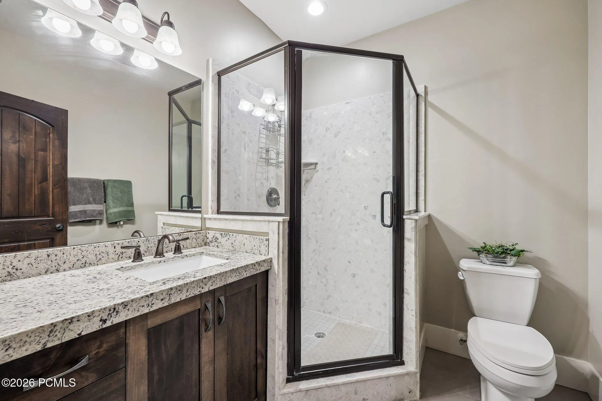 Lower-level full bathroom with a granite vanity and glass-door shower beside the lower guest bedroom in a Rustler at Hideout home.