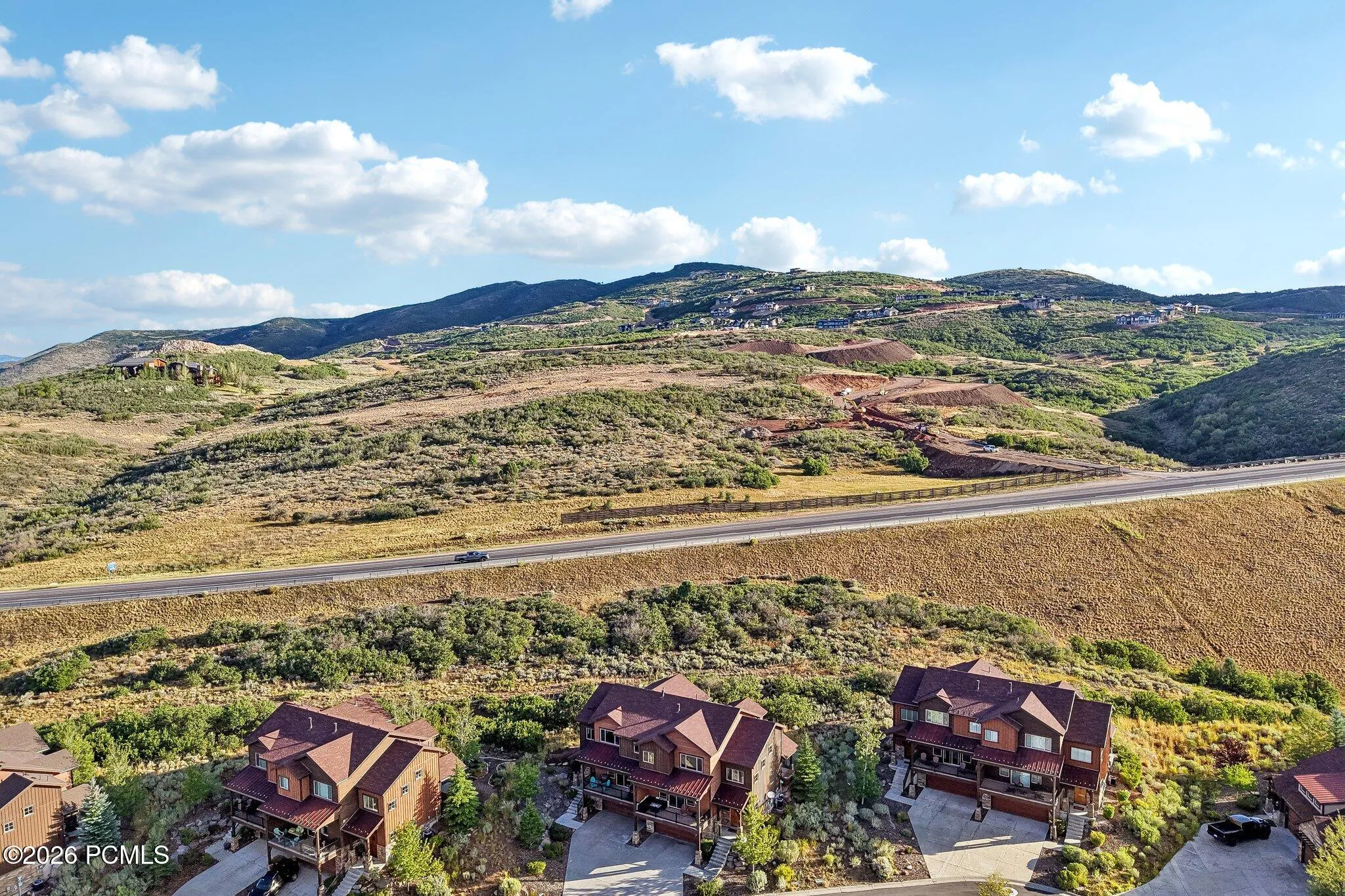 Aerial from the south showing the home against open hillside with the Highway 40 corridor below, about twenty minutes to Park City.