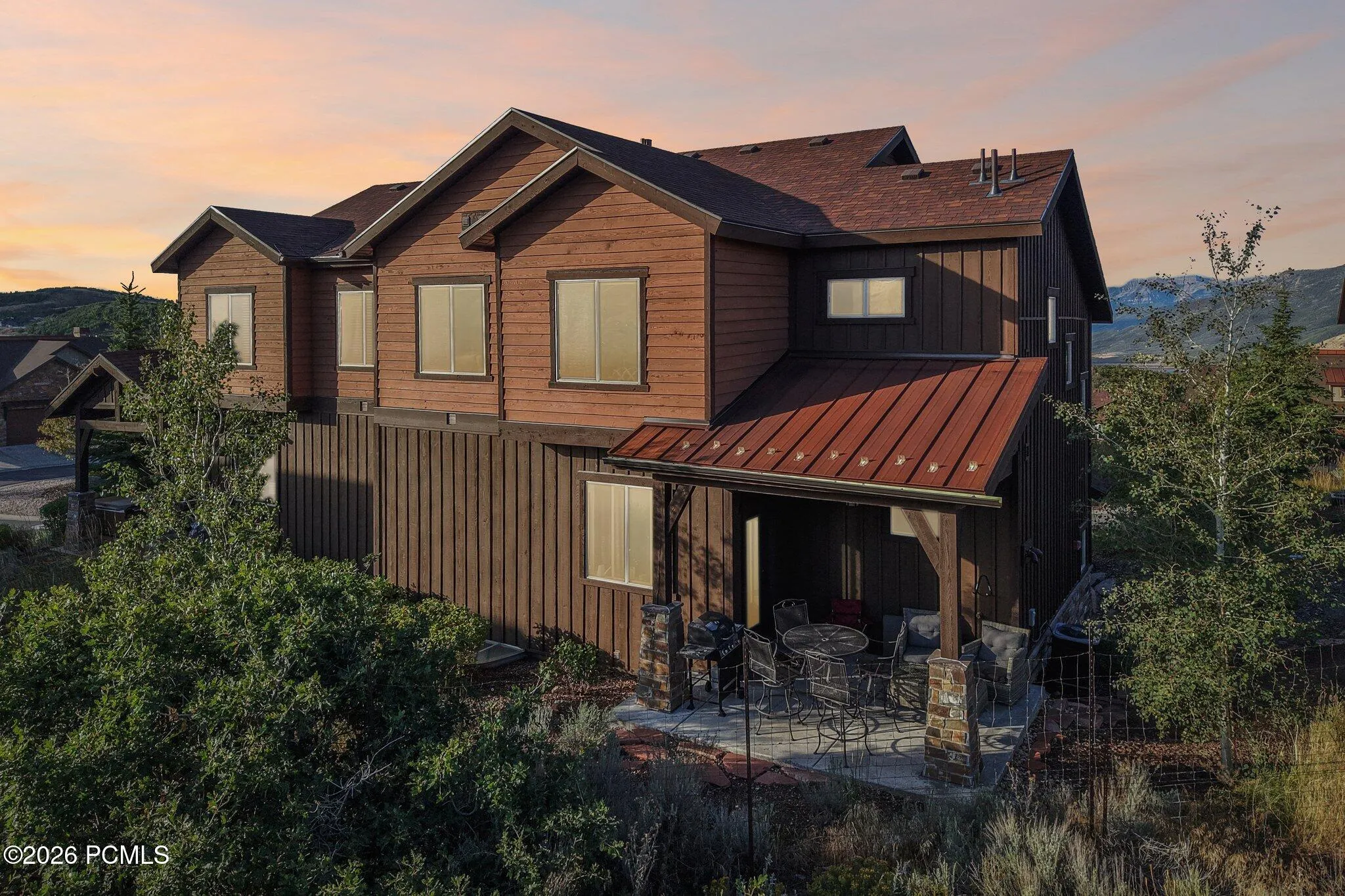 Twilight rendering from the side showing the covered deck stacked over the lower patio in Rustler at Hideout; sky digitally enhanced, everything else as built.