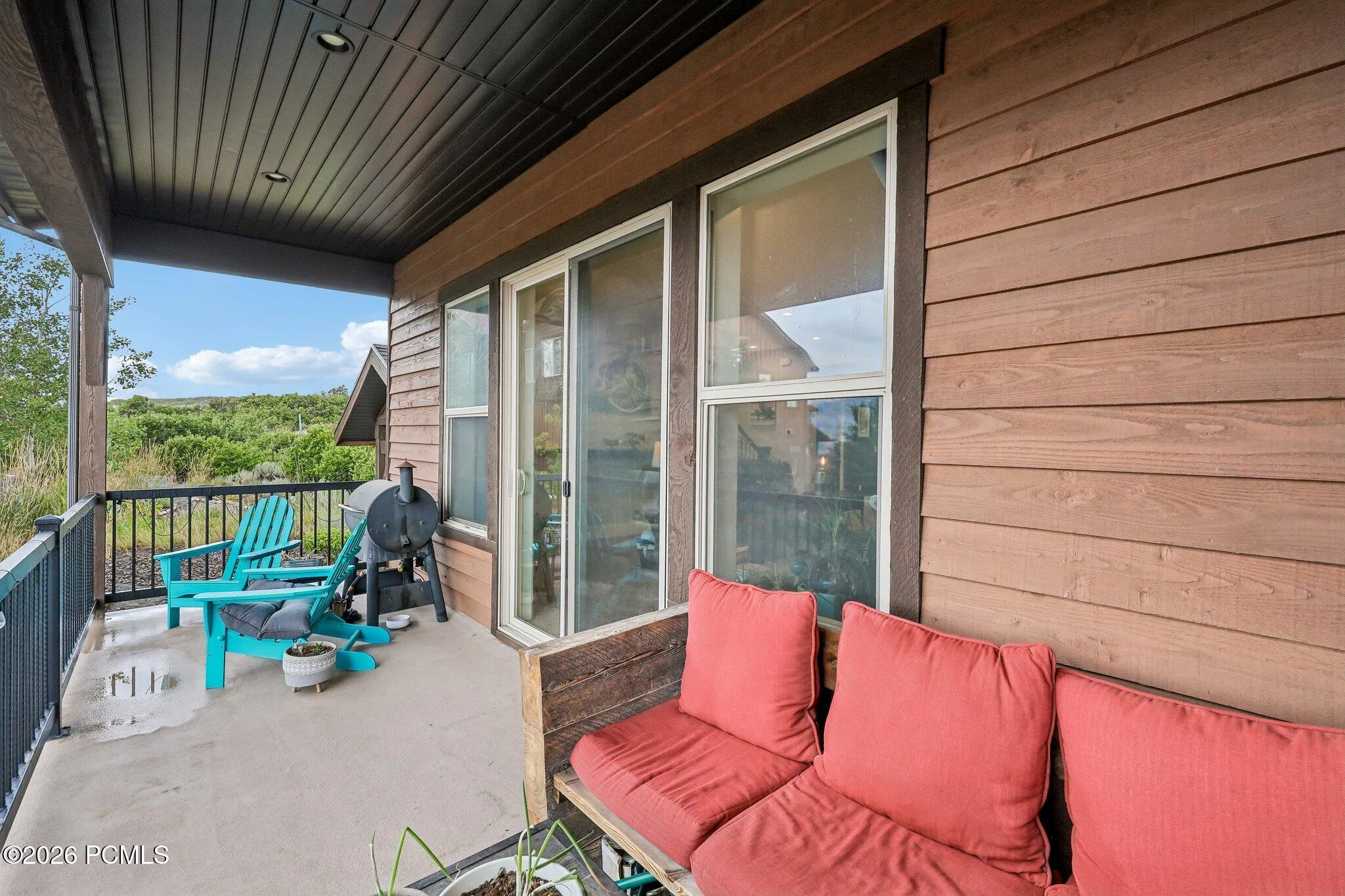 Covered deck off the main level running the full width of the living space, with outdoor seating and Jordanelle Reservoir views.