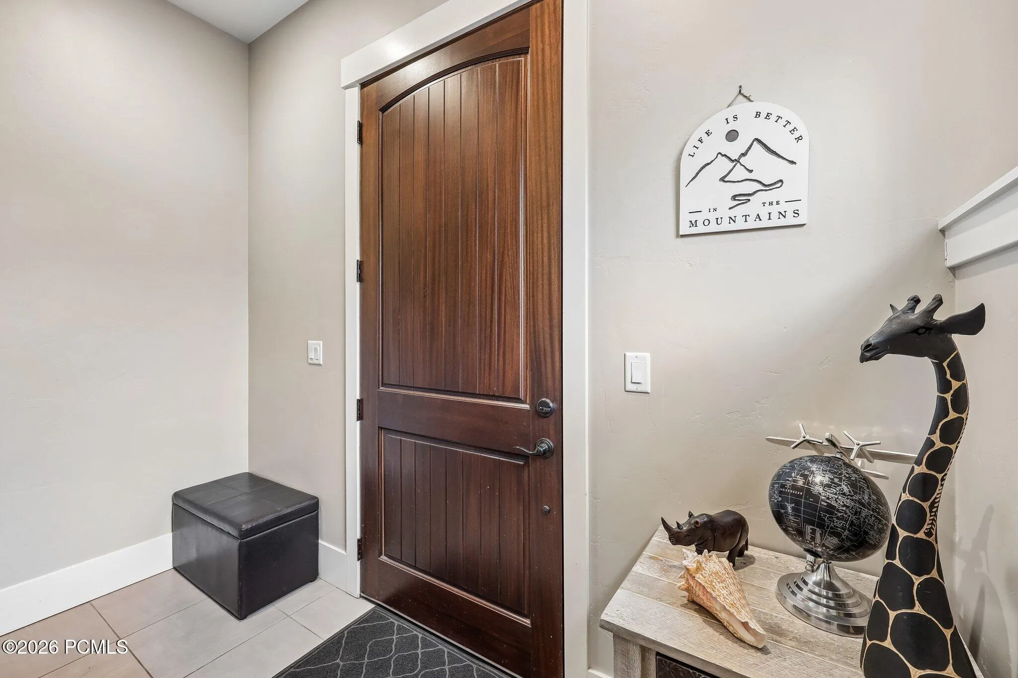 Tiled entry foyer with a stained wood front door and mudroom space inside a Rustler at Hideout home near Jordanelle Reservoir.