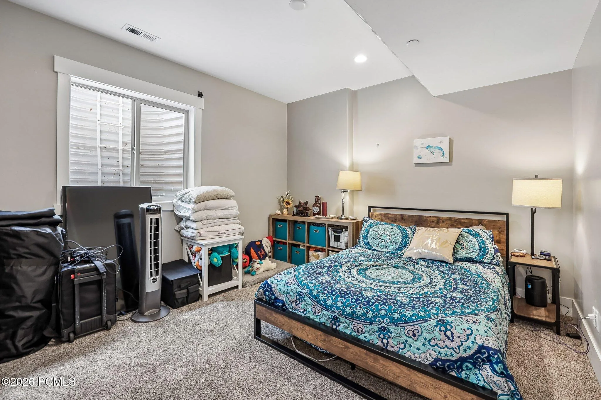 Lower-level guest bedroom with a shuttered window and room for a desk alongside the bed.