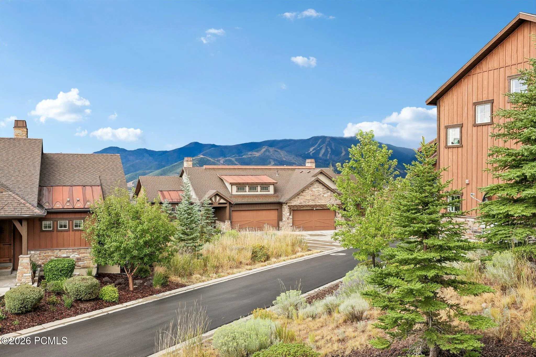 Street view from Viewside Circle of a Rustler at Hideout home with cedar and stone siding and the Wasatch Back behind it.