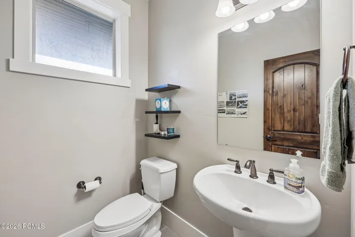 Main-level powder bath off the kitchen with a pedestal sink and knotty alder door in a Hideout, Utah mountain home.