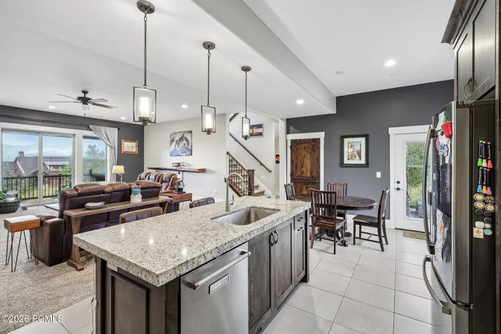 Kitchen island sightline across the great room to the stone fireplace, covered deck and Jordanelle Reservoir beyond, in Hideout, Utah.