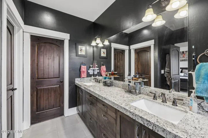 Primary bathroom with a double granite vanity, framed mirrors and a dark accent wall in a Rustler at Hideout home.