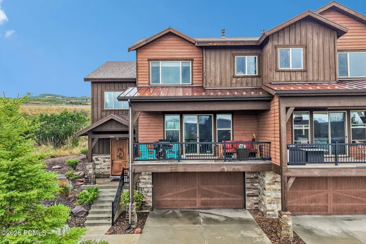 Wood-and-stone front elevation of a Rustler at Hideout home in Hideout, Utah, with a covered main-level deck and tuck-under two-car garage.