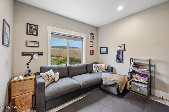 Third upstairs bedroom used as a lounge, with a sectional, desk area and hillside window in a Rustler at Hideout home.