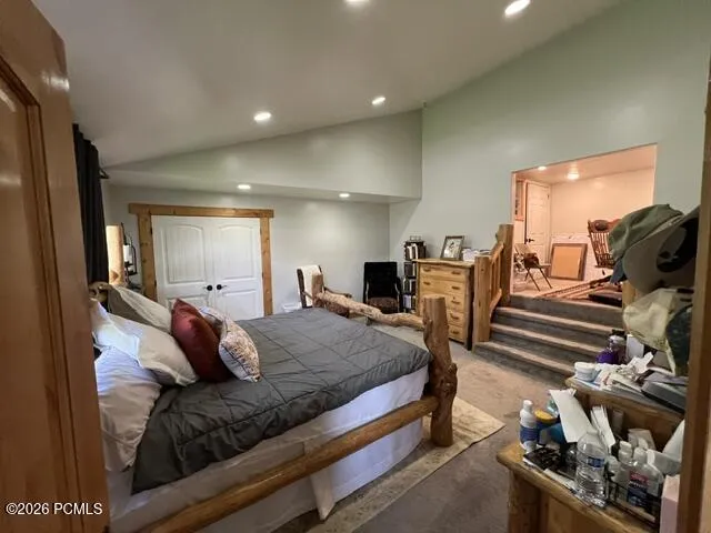 Spacious primary bedroom suite featuring wood-frame bed, tile flooring, recessed ceiling lighting, and an adjoining sitting area with direct access to additional living space