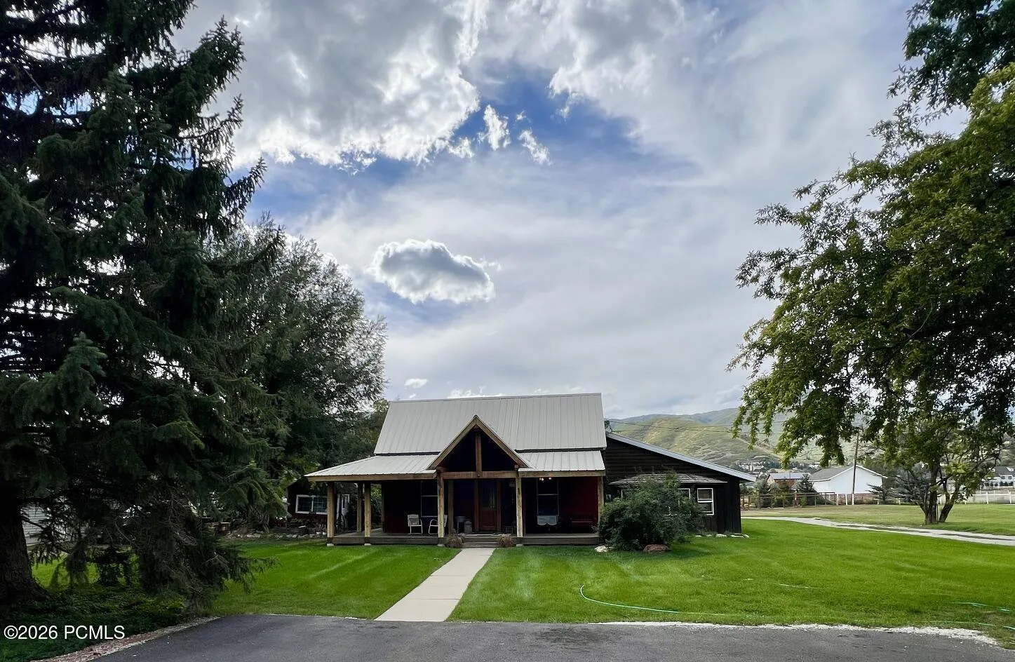 A-frame entry with covered front porch, dark-stained wood siding, and a metal roof