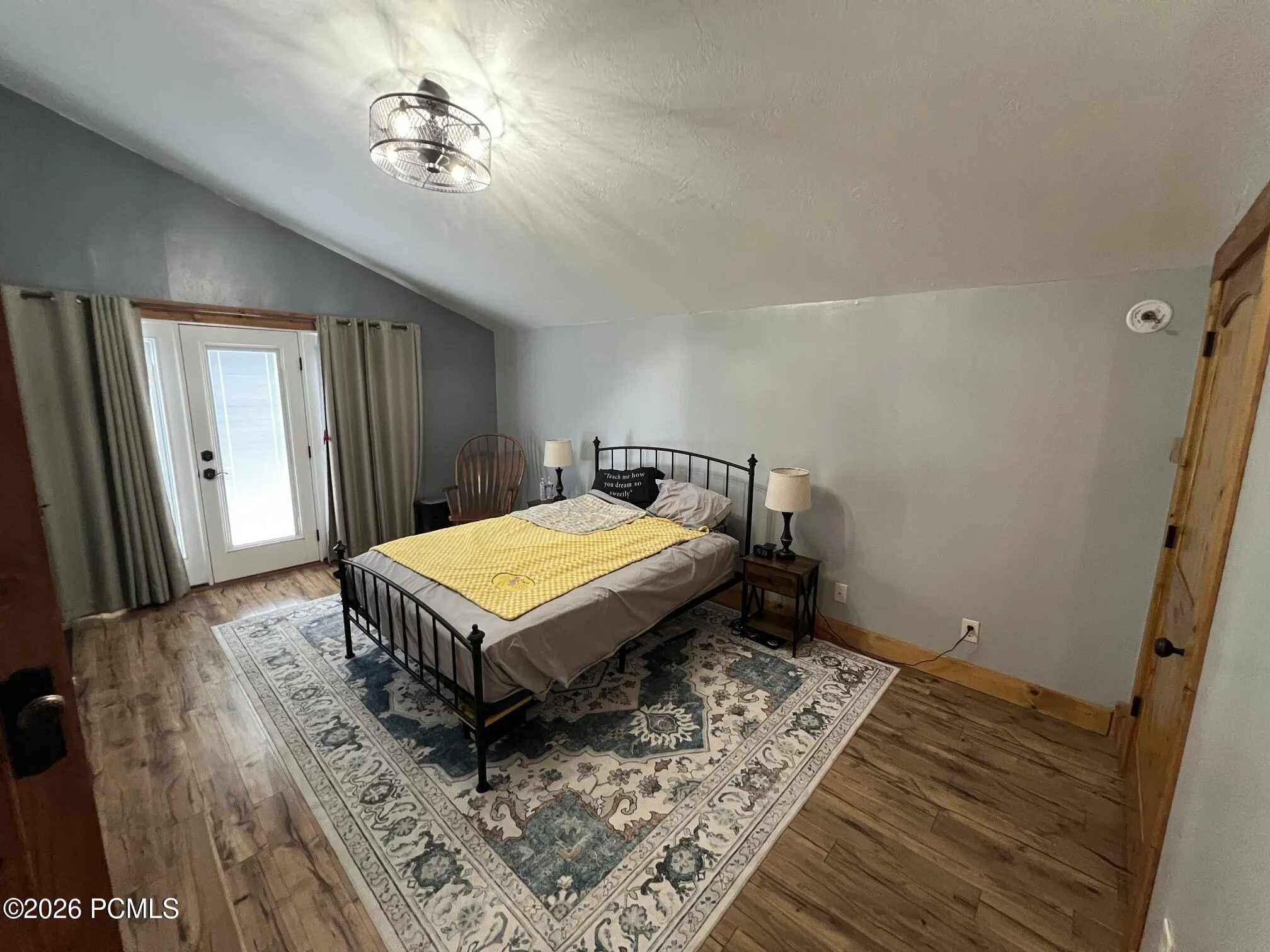 Sloped ceiling with a modern ceiling fan, wood-finish flooring, and a glass-paneled door to personal deck