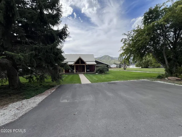 Asphalt Parking pad leading to a residence front door, covered front porch with wood columns, and a landscaped front lawn