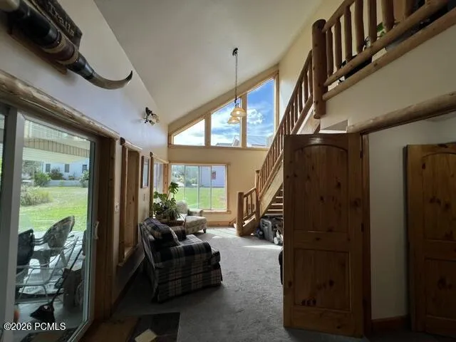 Vaulted ceilings with a prominent wooden staircase and a wood-finish railing