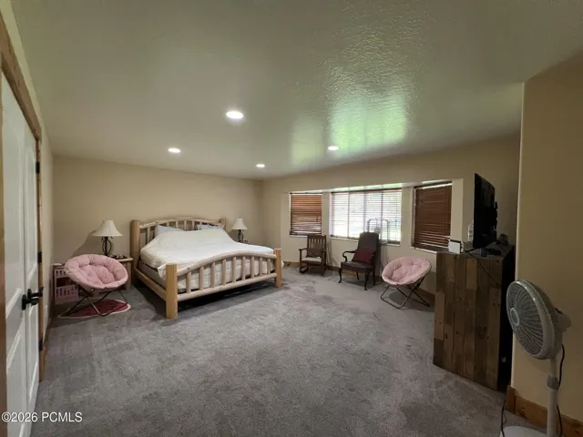 Spacious room with recessed lighting, light-colored walls, carpeted flooring, and window treatments