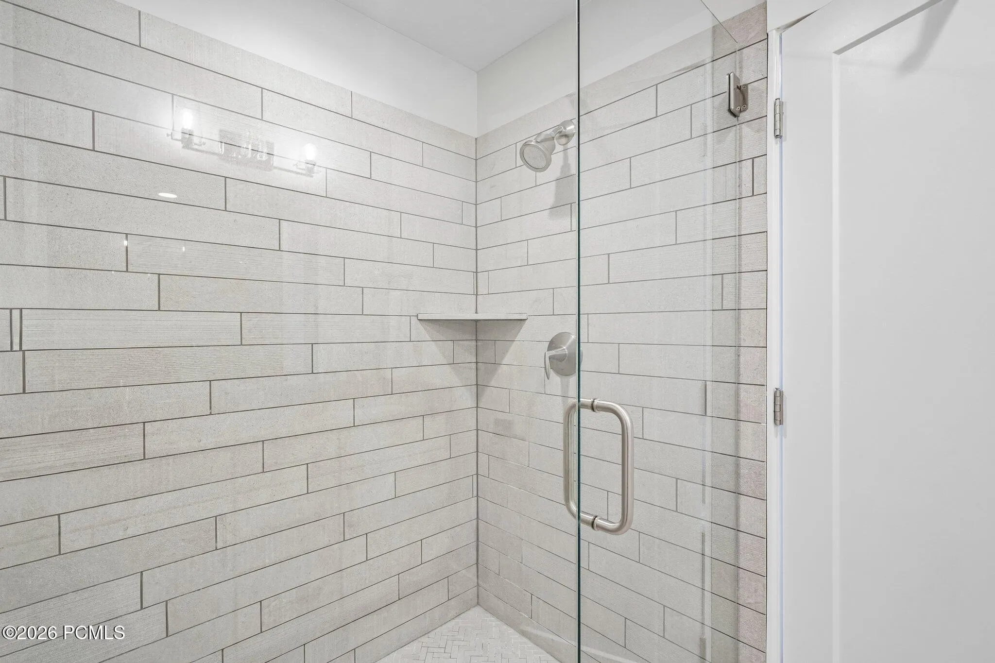 Tiled walk-in shower with glass door and built-in niche.