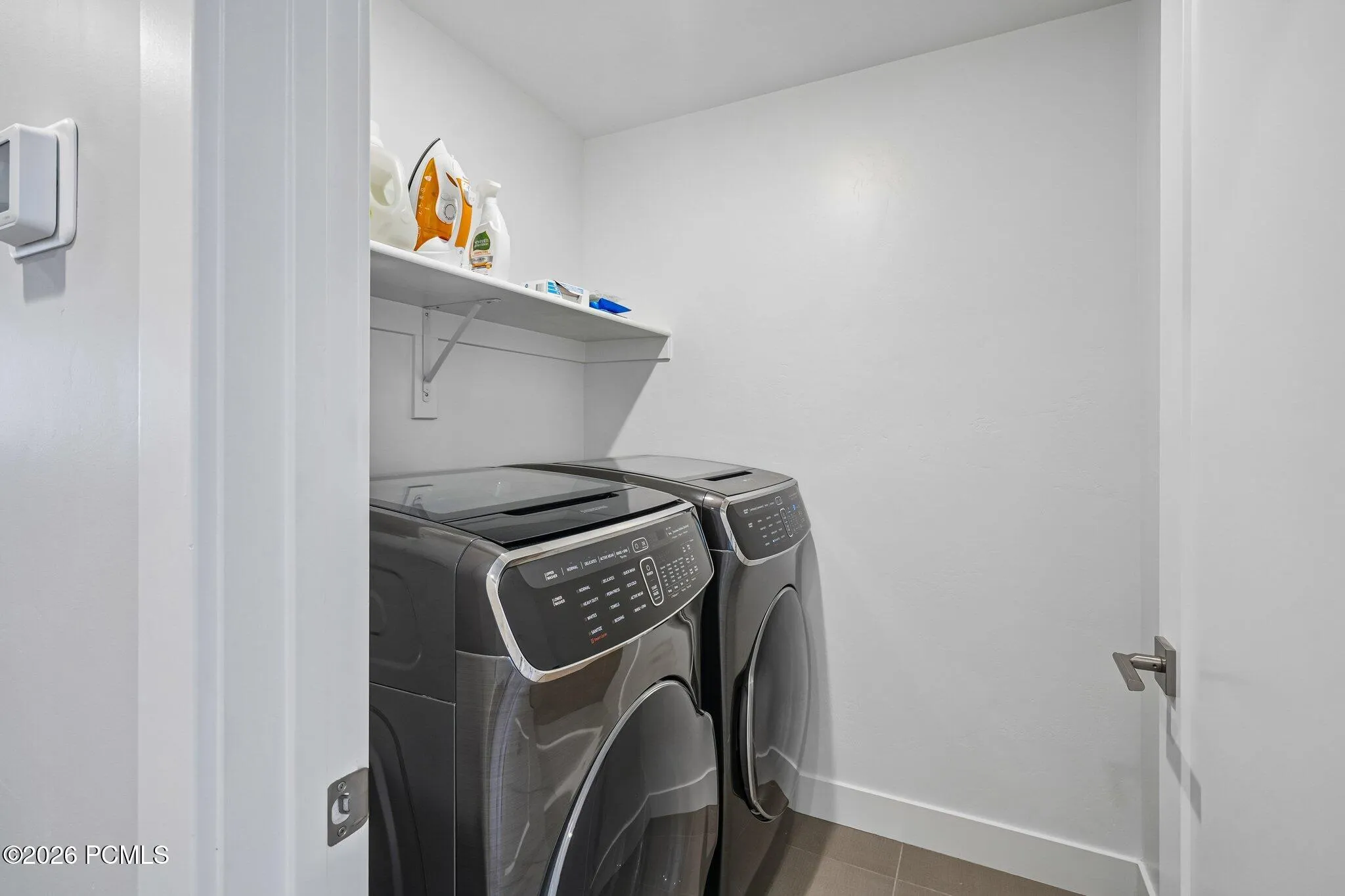 Laundry room with full-size washer and dryer and shelving above.