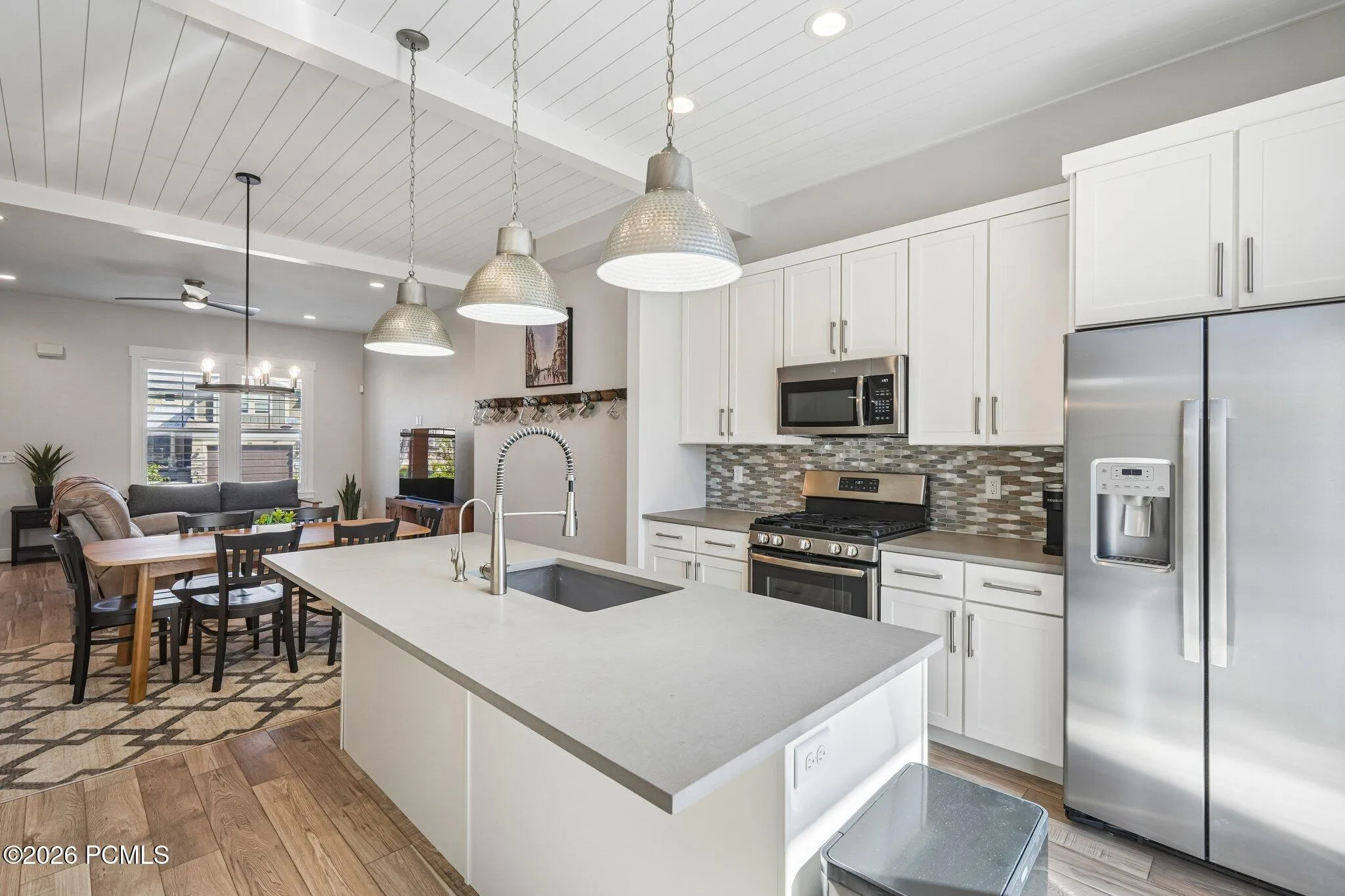 Kitchen with quartz island, stainless appliances, and pendant lighting. Opens to the dining area.