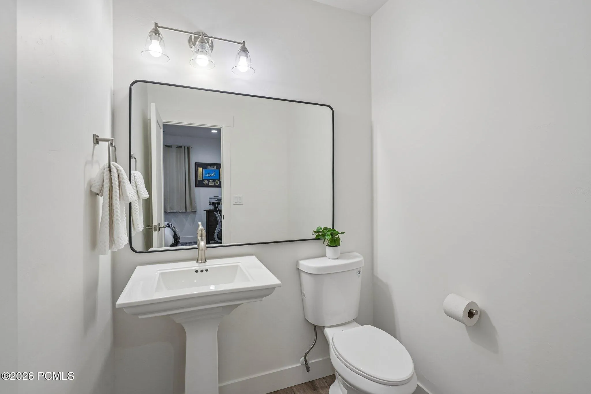 Guest bath with pedestal sink and framed mirror.