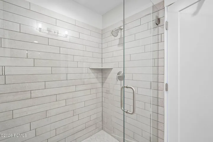 Tiled walk-in shower with glass door and built-in niche.