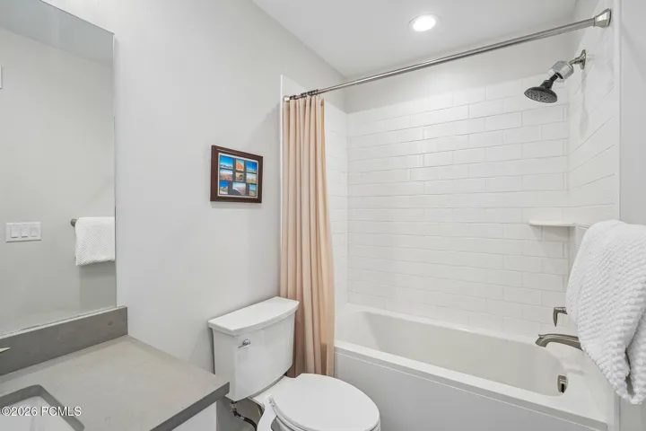 Full bath with tub-shower combination and tile surround.