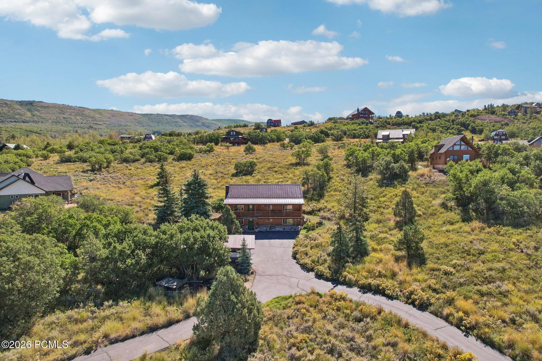 From above, the paved circular drive and the way the trees close in around the lot, under a metal roof made for winter.From above, the paved circular drive and the way the trees close in around the lot, under a metal roof made for winter.Aerial view of the paved circular driveway, metal roof, and treed lot in Timber Lakes, Heber City.
