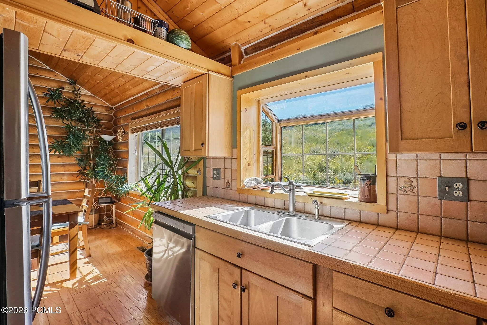 The window over the sink frames the meadow and the ridgeline beyond, turning an ordinary task into one of the better views in the house.
