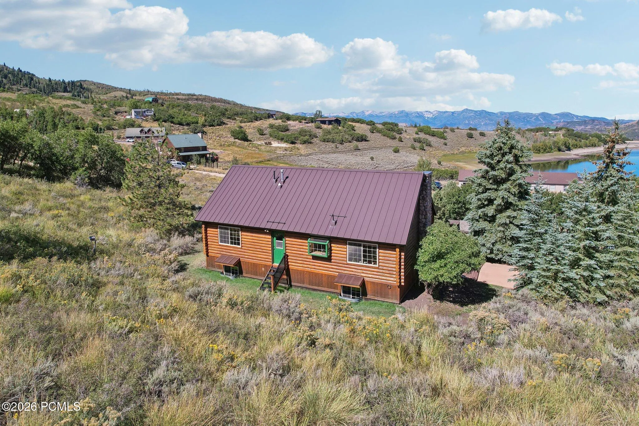 The back of the house from above, with water and mountain ridgelines filling in behind it.The back of the house from above, with water and mountain ridgelines filling in behind it.Aerial rear elevation with lake and mountain ridgelines in the background.
