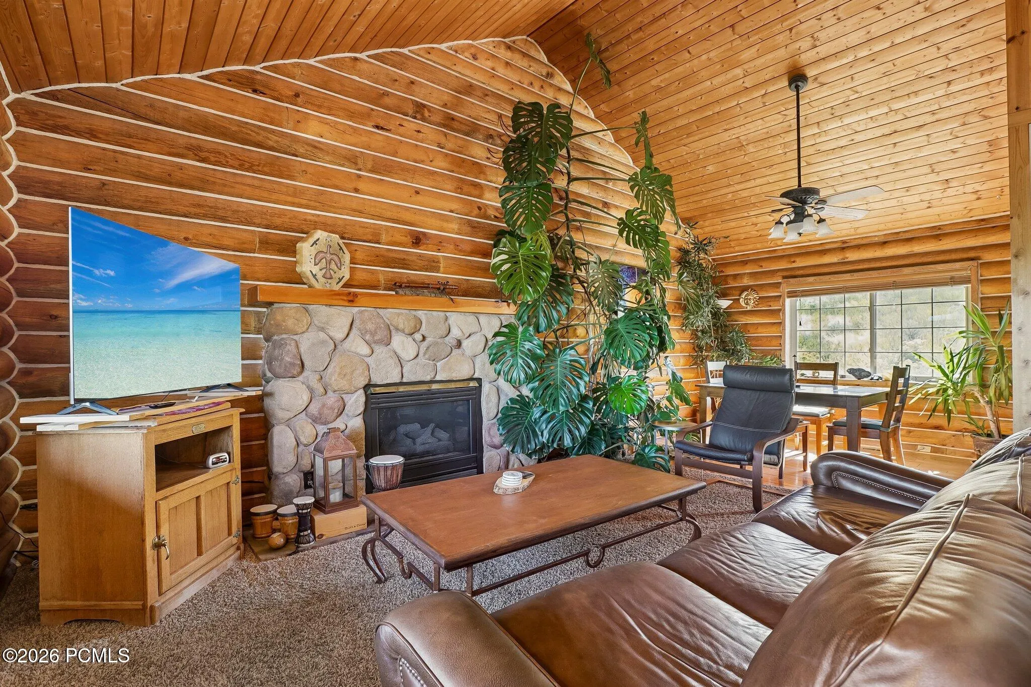 The stone fireplace anchors the great room, with log walls, a vaulted tongue-and-groove ceiling, and room enough to settle in while a storm passes through.