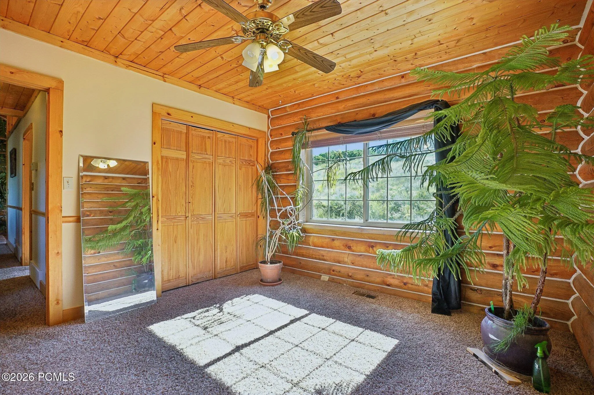 Wood closet doors, a ceiling fan, and steady afternoon light. Easy to see as a guest room, a home office, or a bunk room for ski season.Wood closet doors, a ceiling fan, and steady afternoon light. Easy to see as a guest room, a home office, or a bunk room for ski season.Bedroom with wood closet doors, a ceiling fan, carpeted flooring, and a window on the exterior wall.