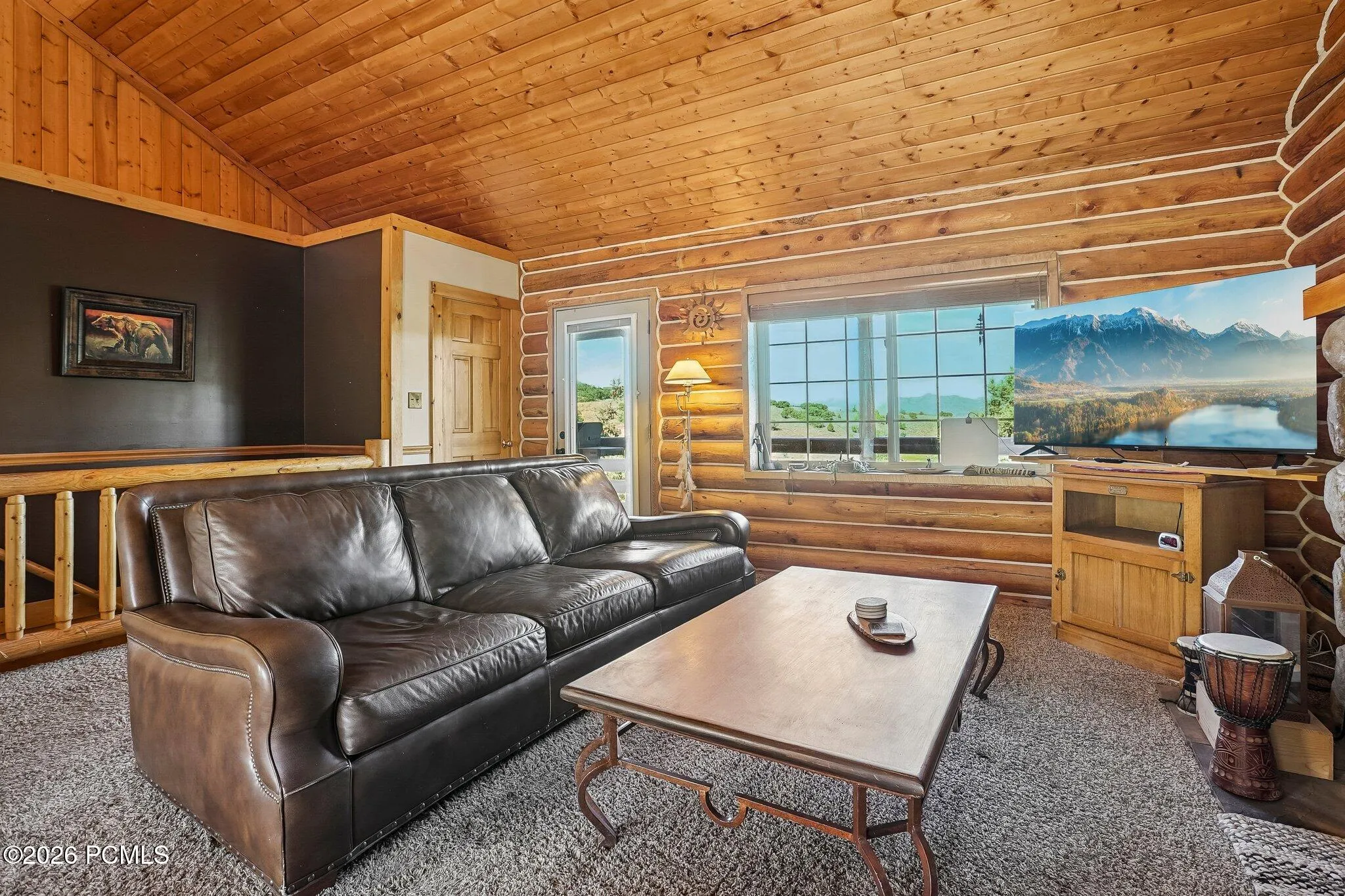 Mountain views through the windows, wood overhead, and a seating area built around the light. This is the room that makes the case for cabin living.