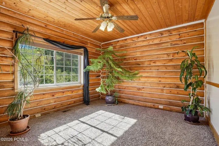 A bedroom with log walls, a vaulted wood ceiling, and a window that opens to wind in the pines.A bedroom with log walls, a vaulted wood ceiling, and a window that opens to wind in the pines.Bedroom with log walls, a vaulted wood ceiling, ceiling fan, and a window facing the hillside.
