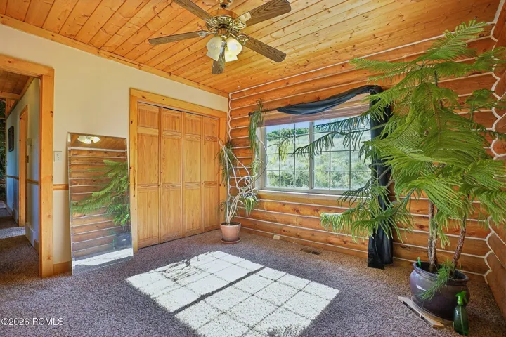 Wood closet doors, a ceiling fan, and steady afternoon light. Easy to see as a guest room, a home office, or a bunk room for ski season.Wood closet doors, a ceiling fan, and steady afternoon light. Easy to see as a guest room, a home office, or a bunk room for ski season.Bedroom with wood closet doors, a ceiling fan, carpeted flooring, and a window on the exterior wall.