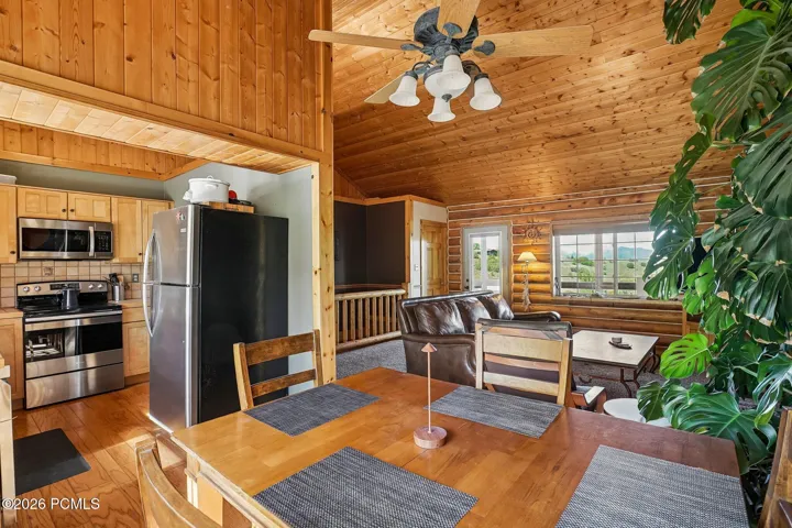 The kitchen opens directly into the living area, keeping whoever is cooking in the conversation. Stainless appliances, wood floors, and the vaulted ceiling carrying through.