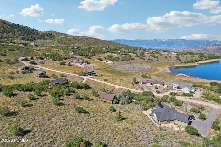 An aerial over the water with cabins scattered around it and mountains rising behind. This is the setting buyers come to Timber Lakes for.An aerial over the water with cabins scattered around it and mountains rising behind. This is the setting buyers come to Timber Lakes for.Aerial view of a lake and surrounding cabins in Timber Lakes, Heber City, with mountain ranges beyond.