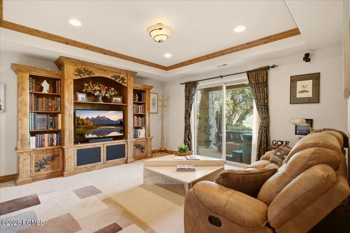 Built-in entertainment center with integrated shelving, recessed lighting, wood-finish ceiling trim, and sliding glass door access to the patio