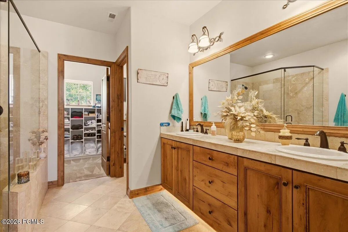 Owner's Bathroom featuring a dual vanity with wood-finish cabinetry, a large framed mirror, and integrated lighting