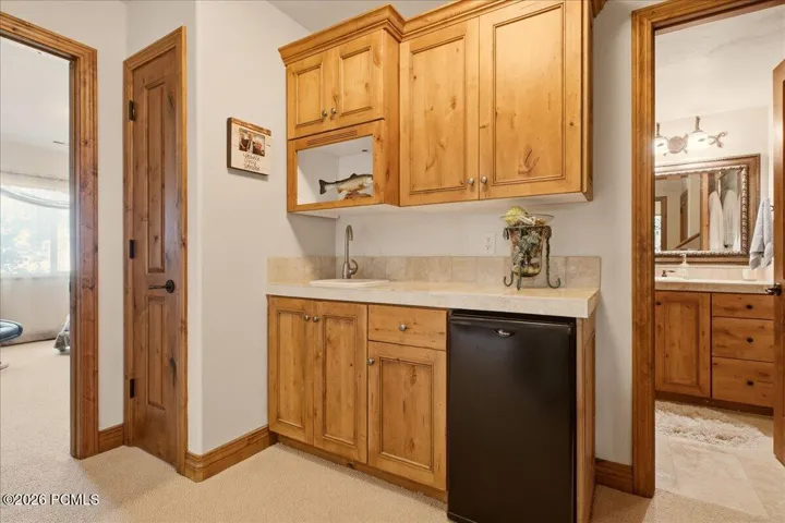 Wet bar featuring wood-finish cabinetry, a built-in sink, and an integrated compact refrigerator