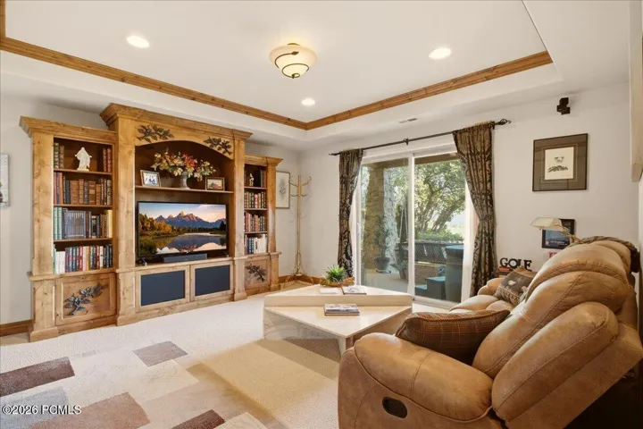 Built-in entertainment center with integrated shelving, recessed lighting, wood-finish ceiling trim, and sliding glass door access to the patio