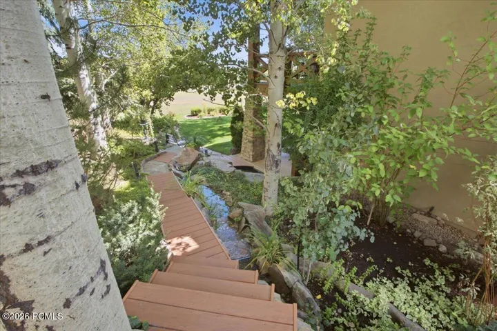 Landscaped outdoor area featuring a wood-finish pathway, stairs, and a water feature